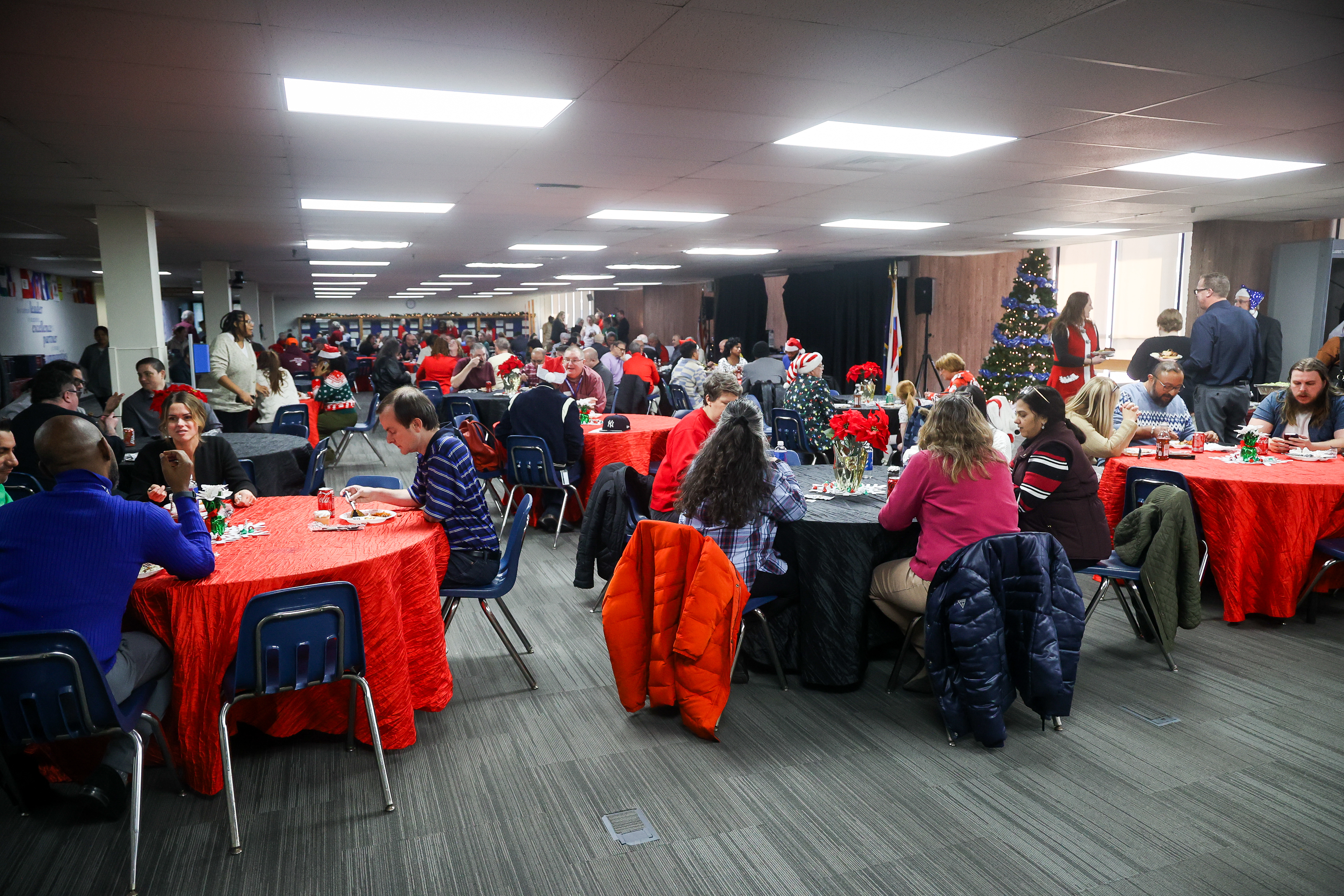 People gather in a large room eating at a holiday party.