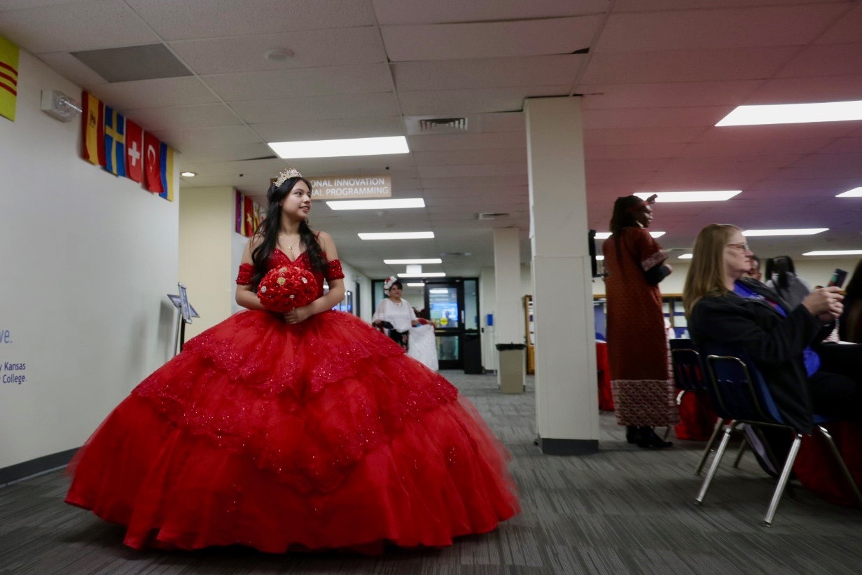 Girl walks down aisle in red dress.