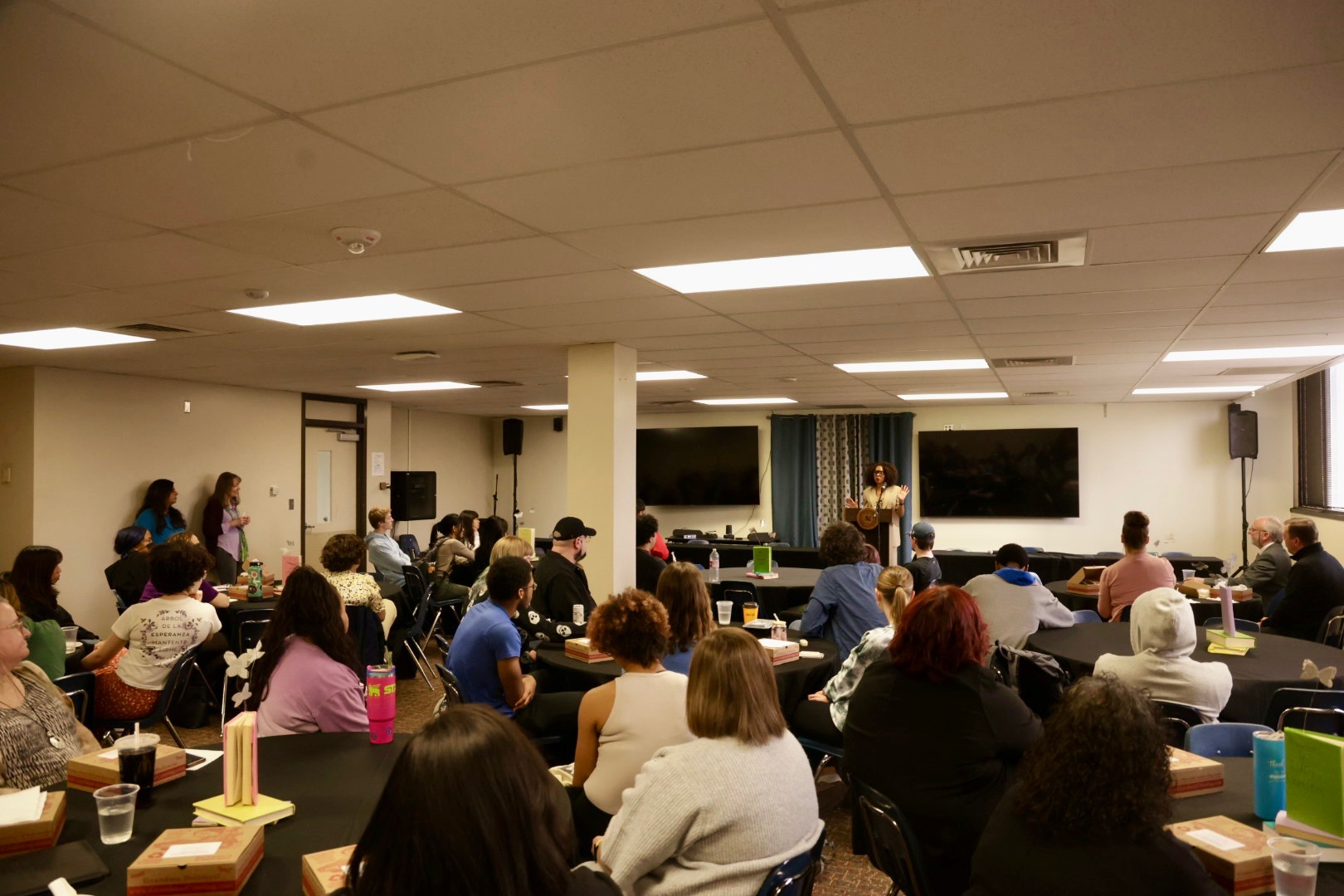 Room full of people listening to speaker in front of the room.