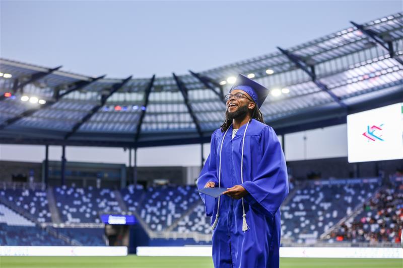 Graduate standing in the middle of an arena.