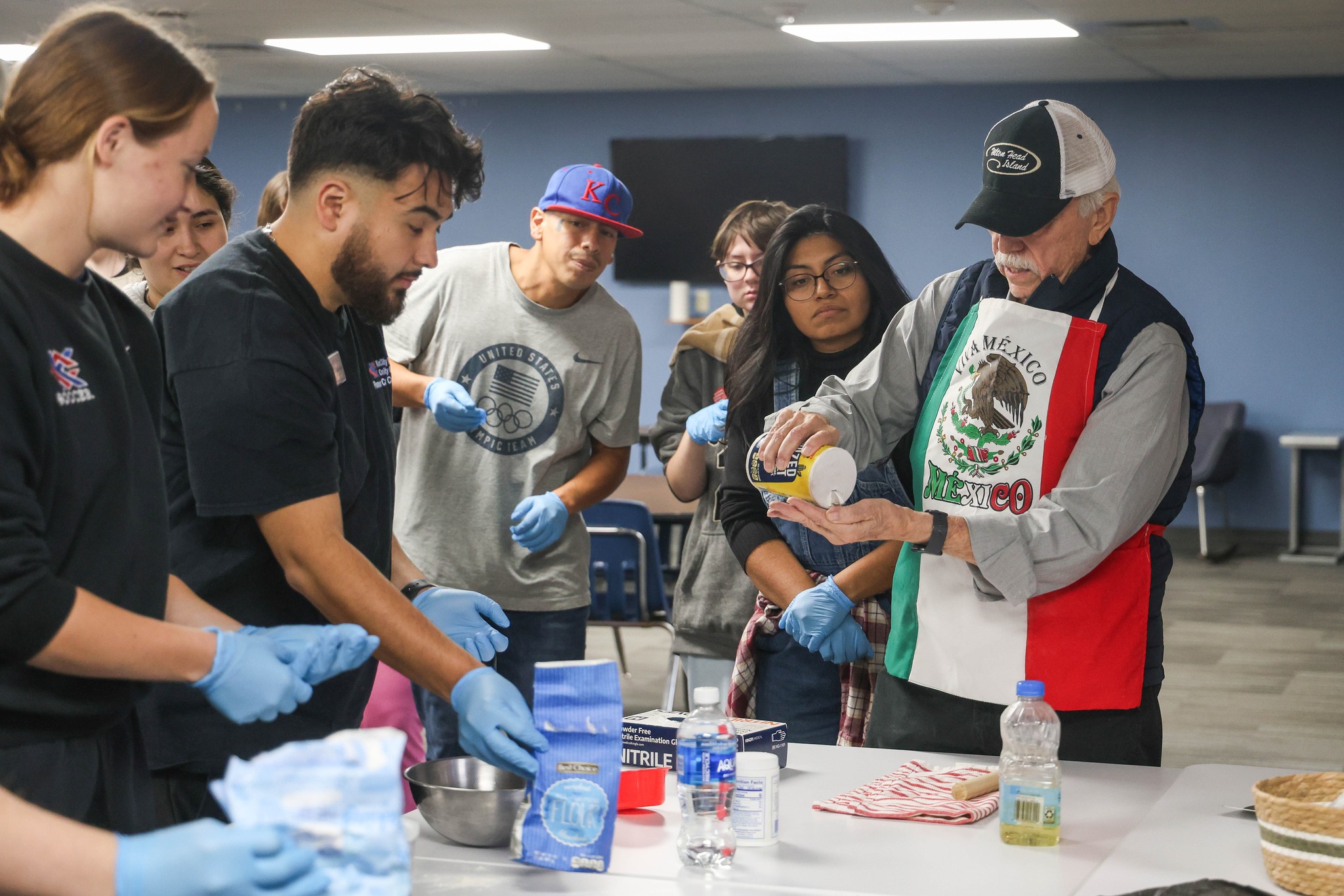 Group of people standing around man making tortillas.