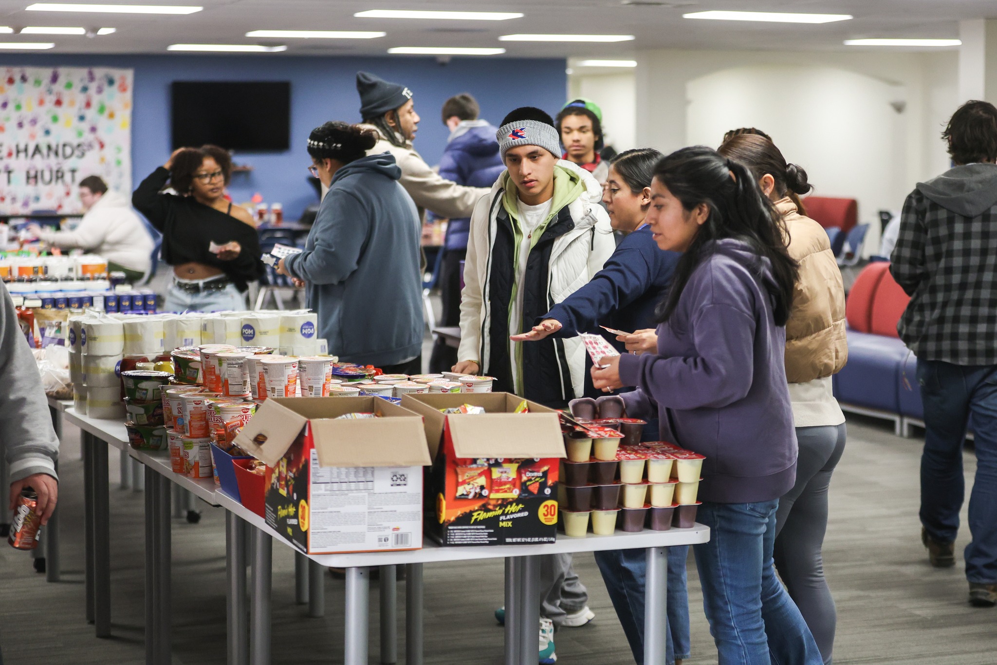 Students choosing groceries from table.