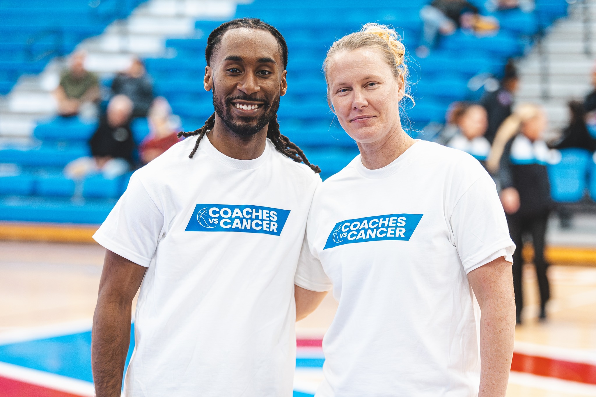 Man and woman standing with Coaches vs. Cancer t-shirts.