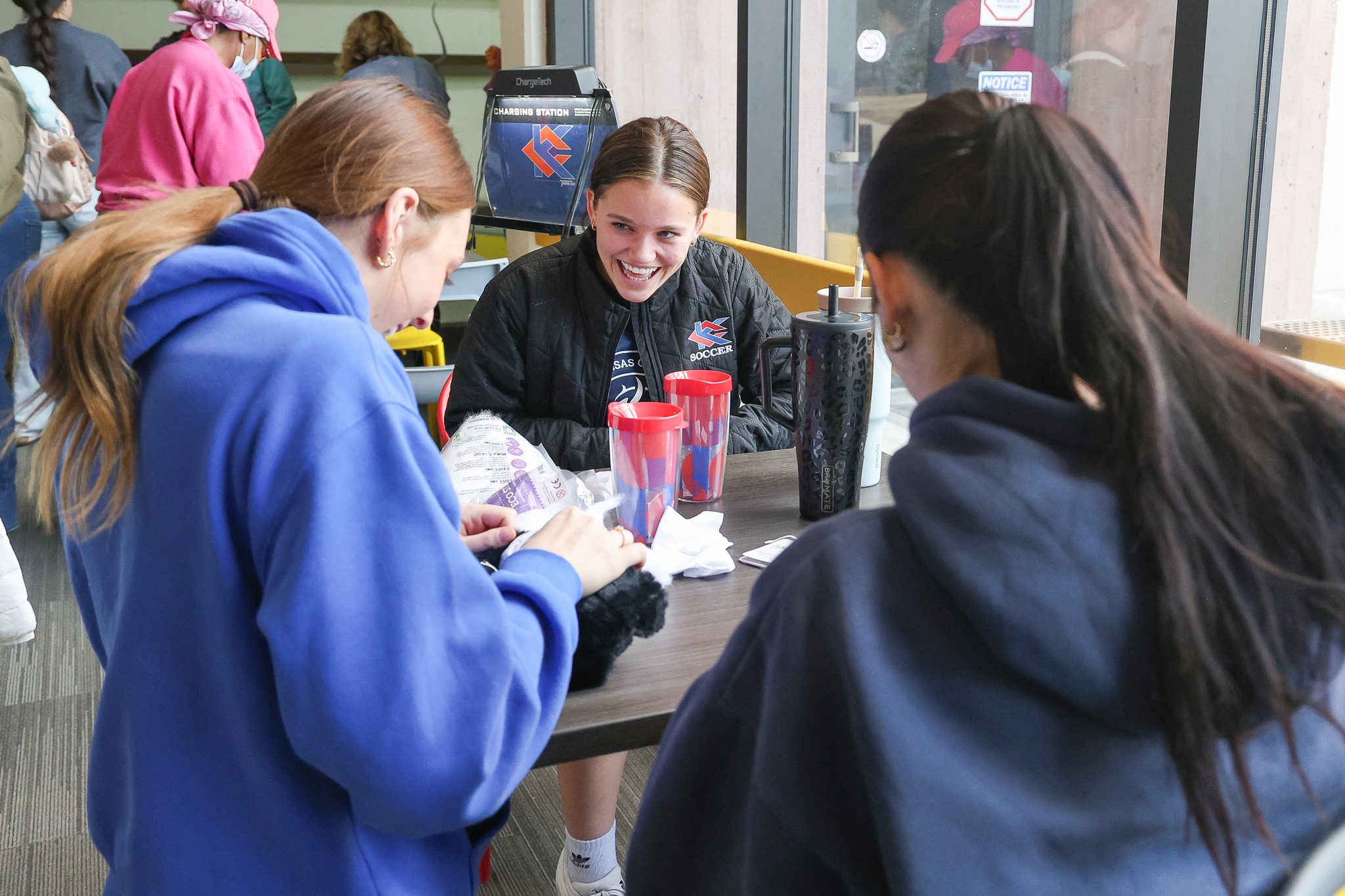 Three girls standing around a table stuffing a plush animal.