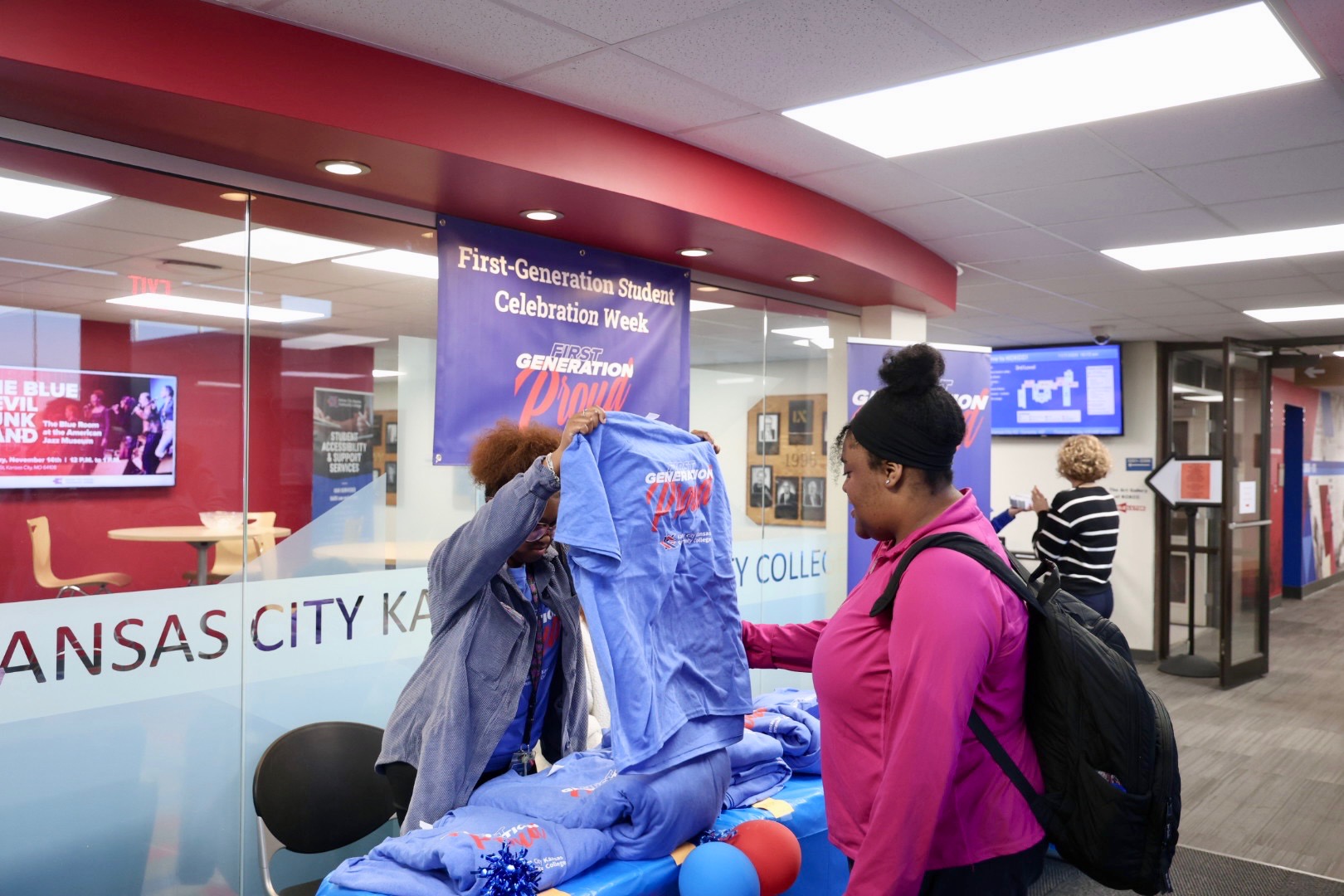 Student standing in front of table, getting a t-shirt