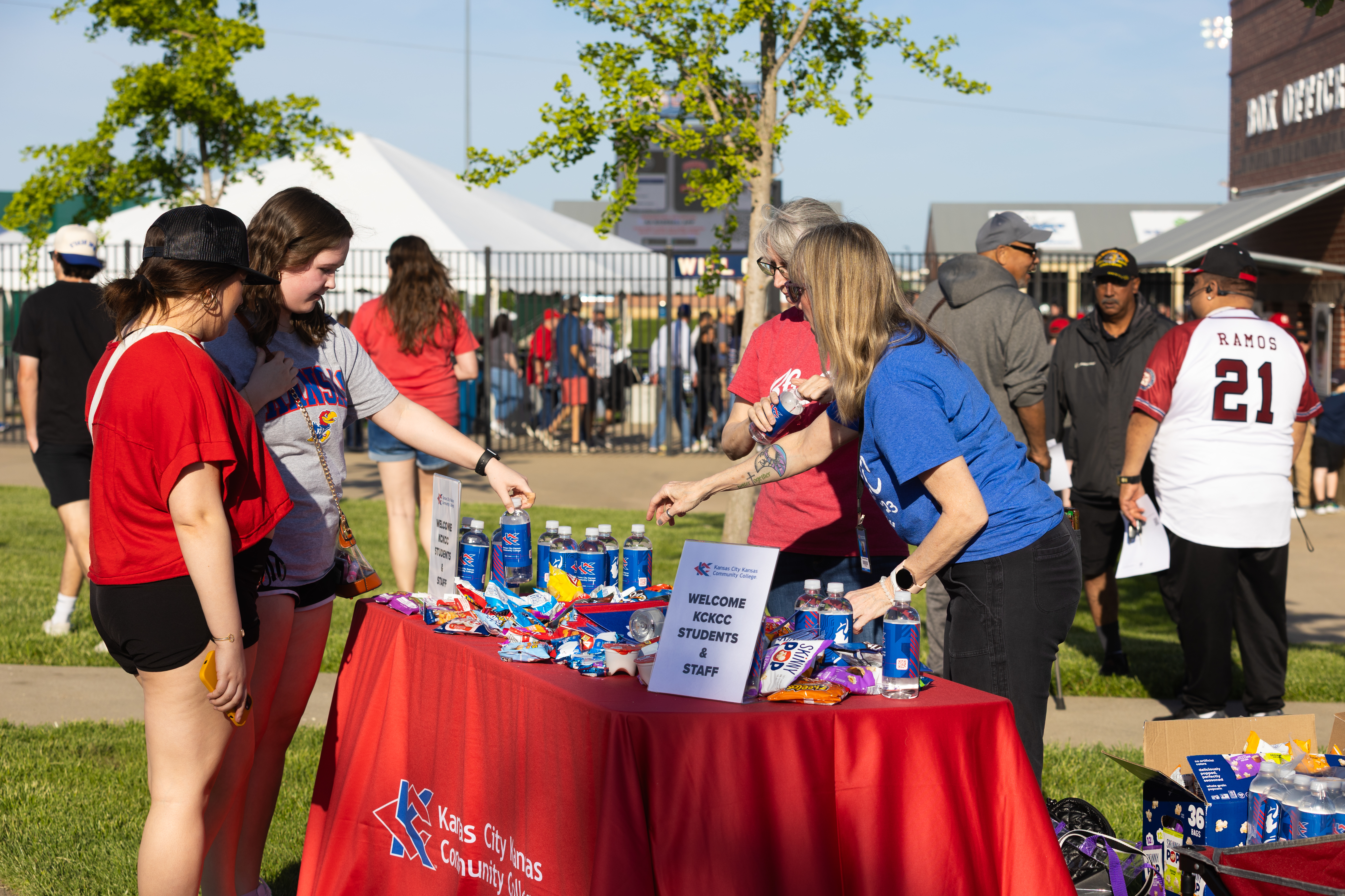 KCKCC employees giving items to students at baseball game.