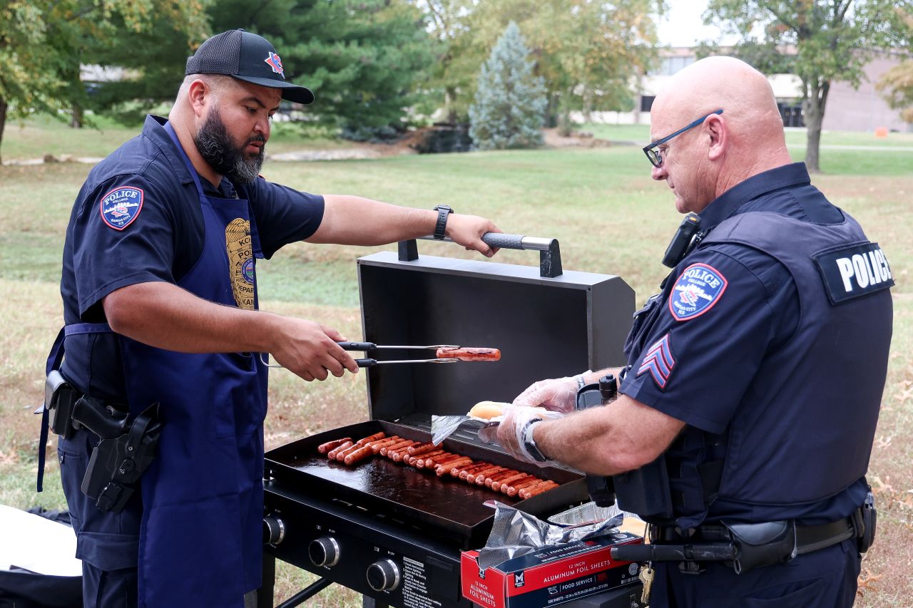 Two police officers grilling hot dogs.