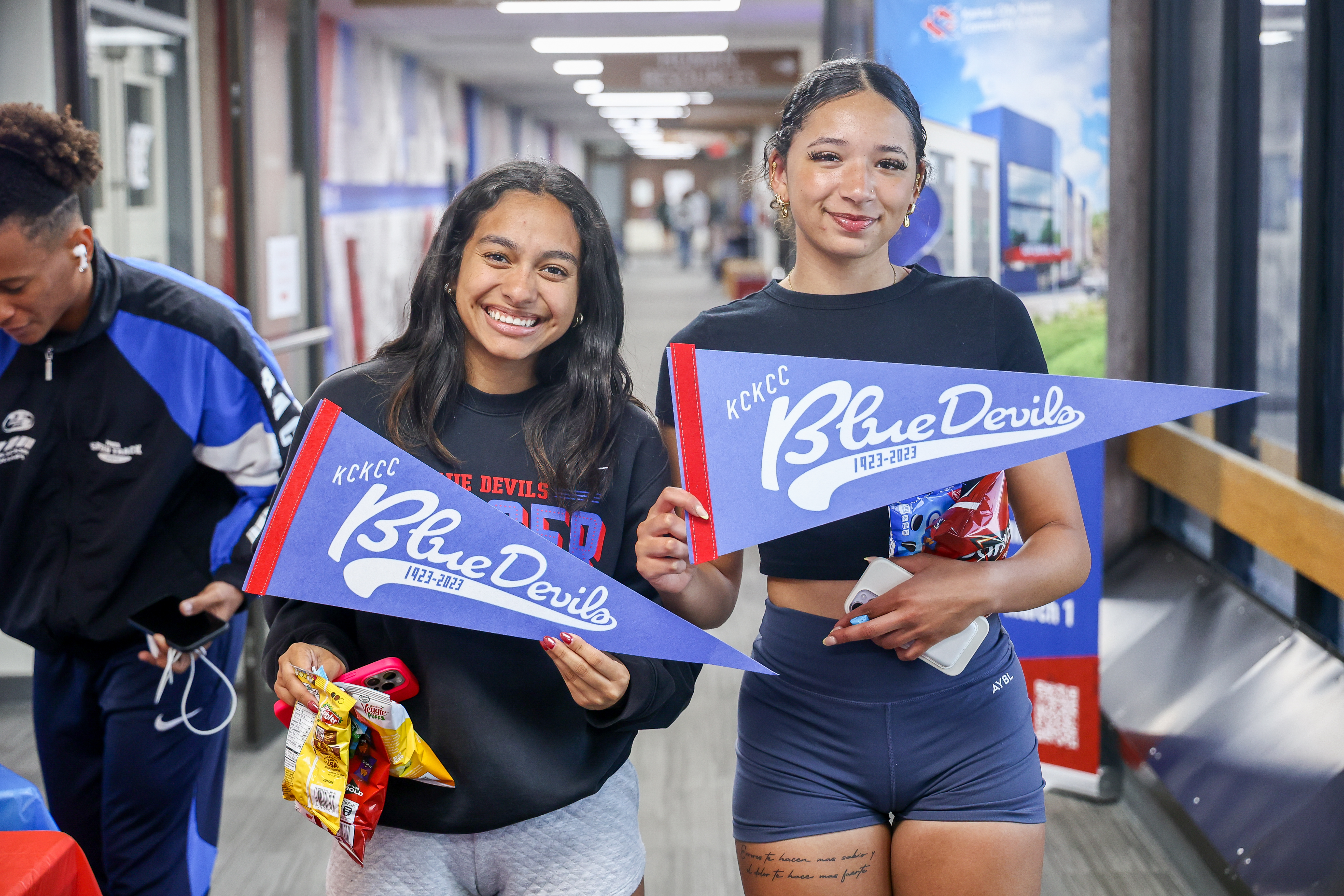 Two girls holding KCKCC pennants.