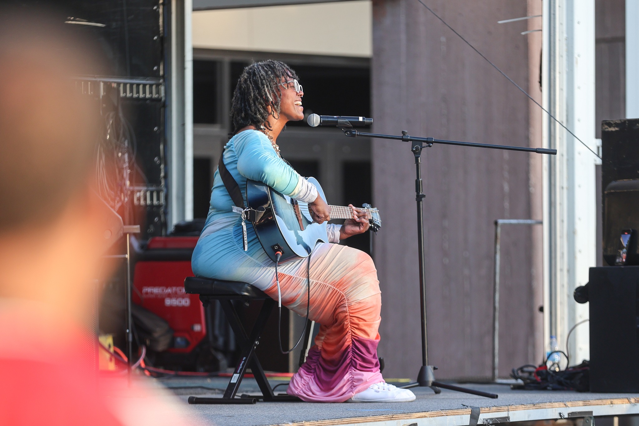 Woman with guitar singing on stage.