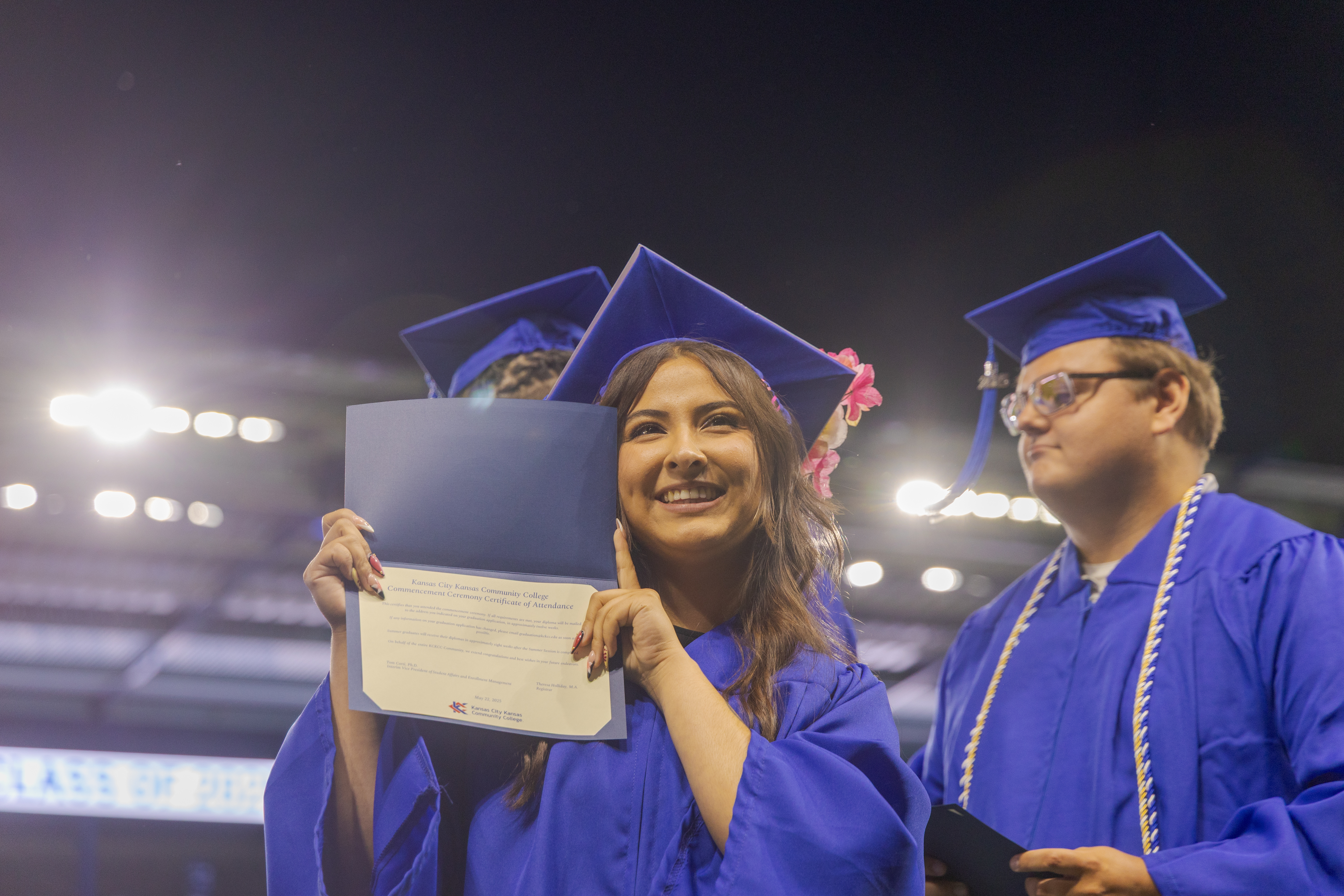 Girl in blue gown holding diploma.