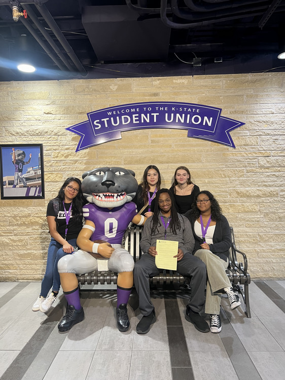 Students sitting with a statue of Willie Wildcat.
