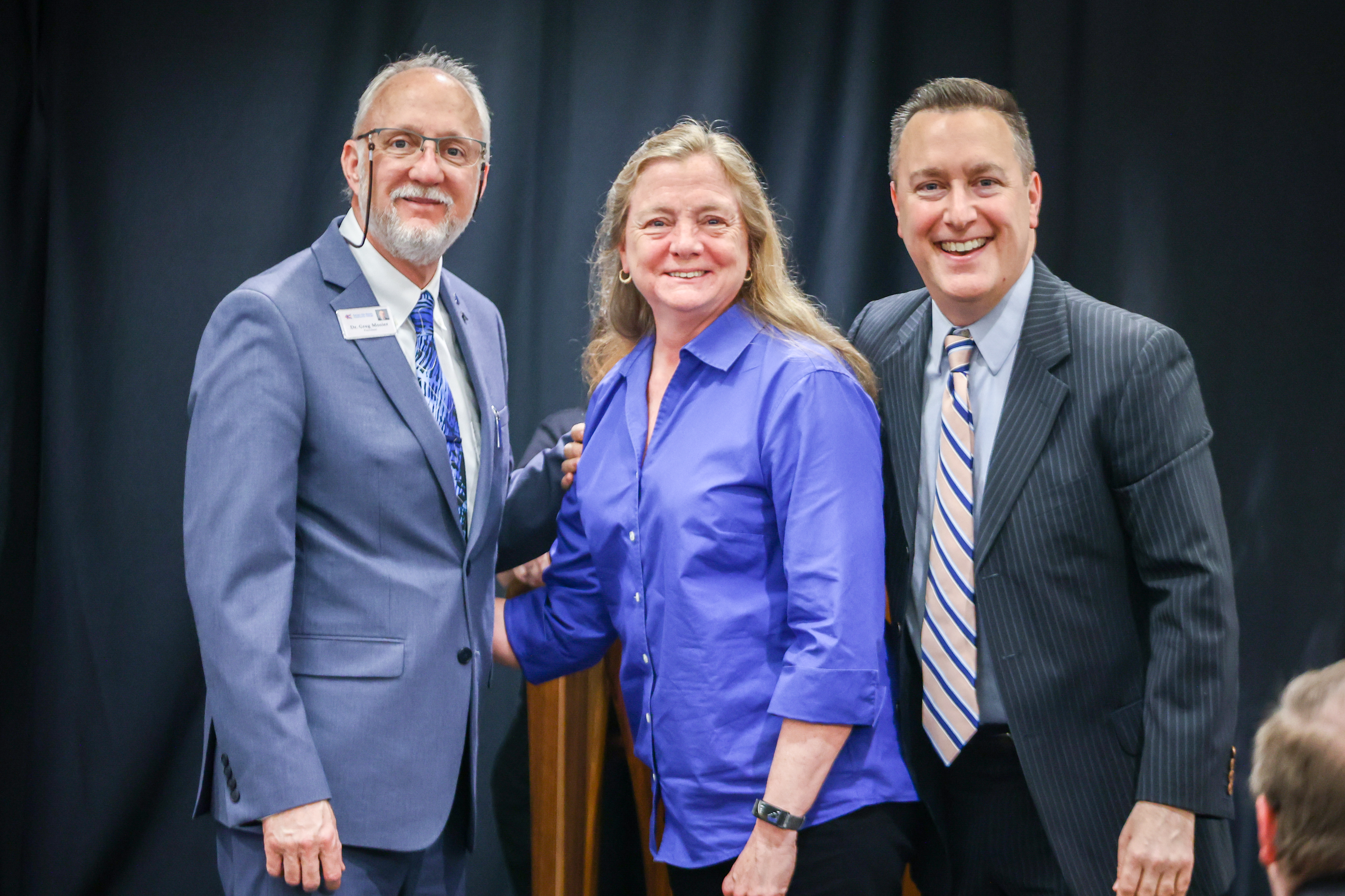 Two men and one woman stand together at event.