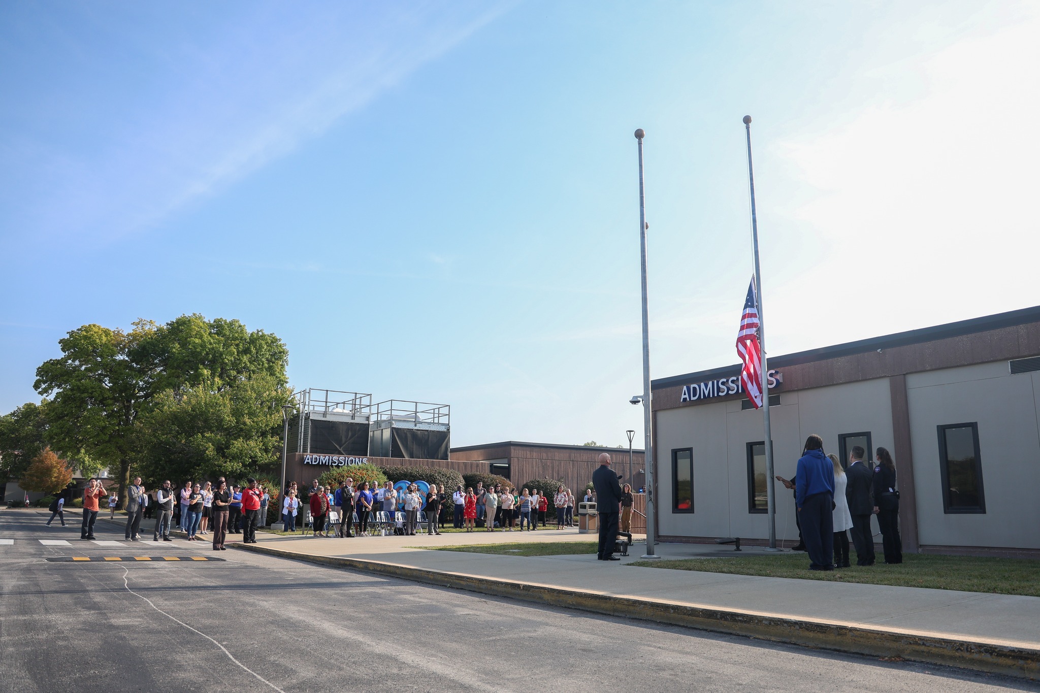 Group of people looking at American flag as it is being raised.